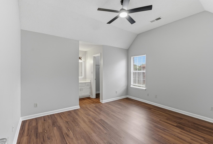 Spacious room featuring vaulted ceilings, wood-finish flooring, a contemporary ceiling fan, and ample natural light from the window