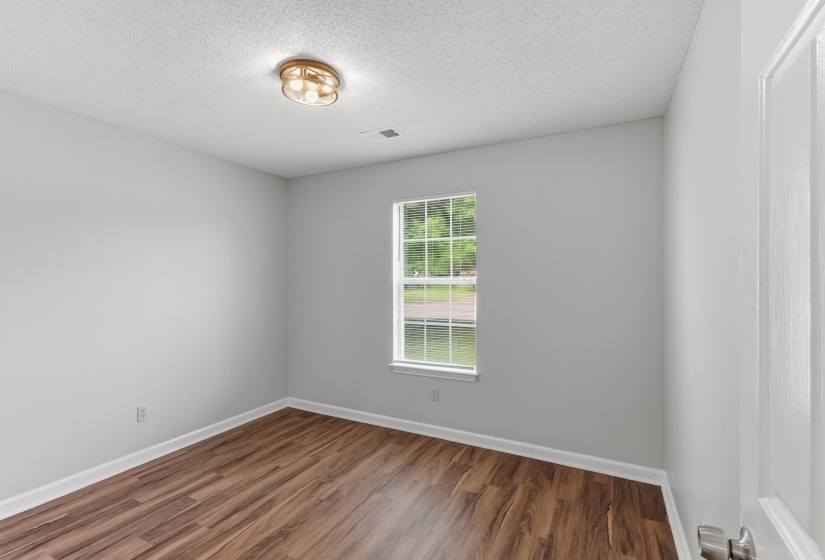 Room featuring wood-finish flooring, light gray walls, and white trim