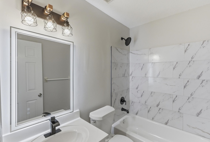 Bathroom featuring a white bathtub, toilet, and vanity with a rectangular sink