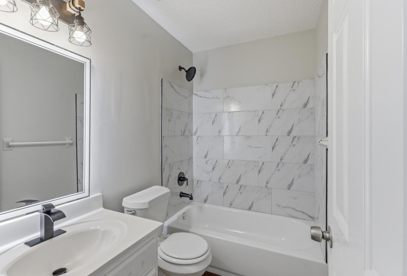 Bathroom featuring a white vanity with an integrated sink, black faucet, and frameless mirror