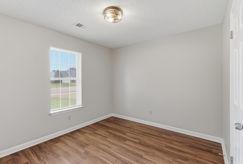 Wood-finish flooring with white baseboards and neutral wall paint
