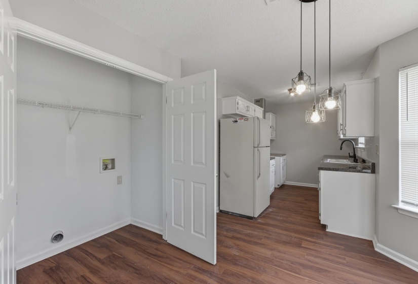 Kitchen area featuring wood-finish flooring, white cabinetry, dark countertops, and a stainless steel sink with a black faucet
