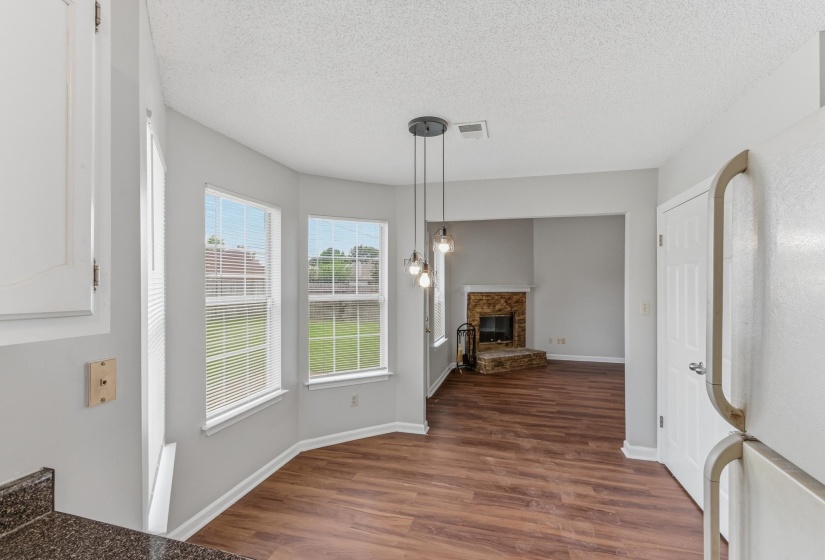 Dining area with bay windows, wood-finish flooring, and pendant lighting