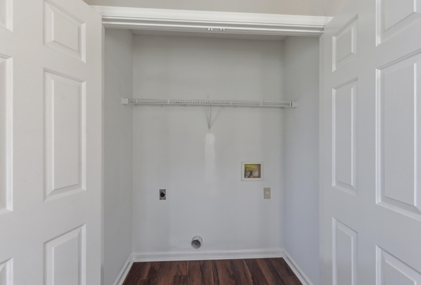 Dedicated laundry area featuring wood-finish flooring, light gray walls, and a wire storage shelf