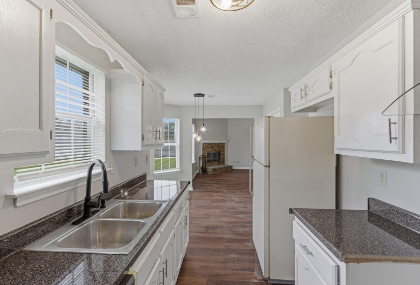 Kitchen featuring a stainless steel double sink with a matte black faucet, dark speckled countertops, and white cabinetry