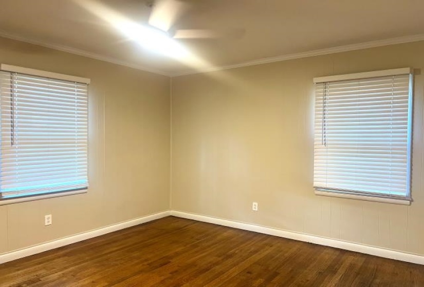 Primary Bedroom featuring wood-finish flooring, two window openings with blinds, crown molding, and a ceiling fan with integrated lighting