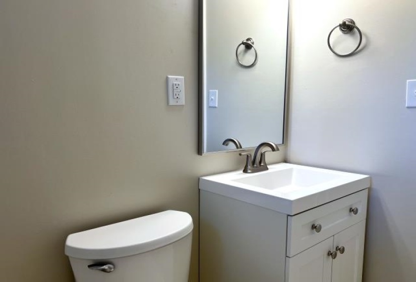 Bathroom featuring a modern white vanity with a rectangular integrated sink, brushed nickel faucet, and a wall-mounted mirror