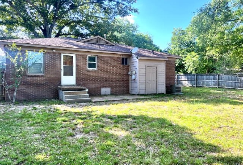 Red brick exterior with a wood fence and a detached storage shed