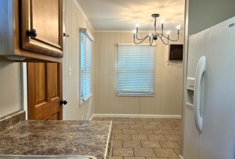 Dining area featuring tile flooring, beadboard wall paneling, and an overhead chandelier light fixture