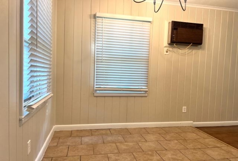 Interior space featuring ceramic tile flooring, vertical paneling walls, and two windows with blinds