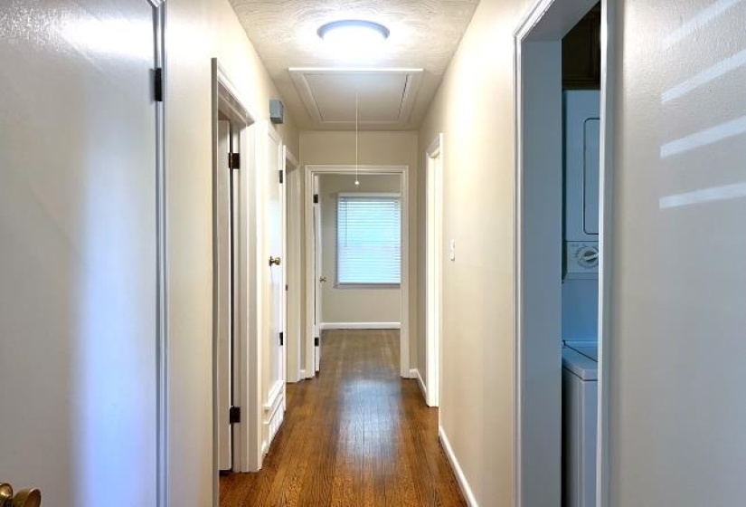 Hallway with wood-finish flooring and multiple doorways