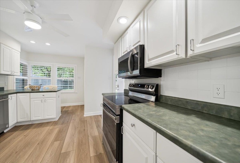 White cabinetry and wood-finish flooring define this kitchen space