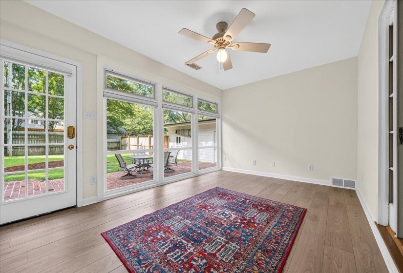 Bright interior space featuring wood-finish flooring, a ceiling fan with light fixture, and neutral wall tones