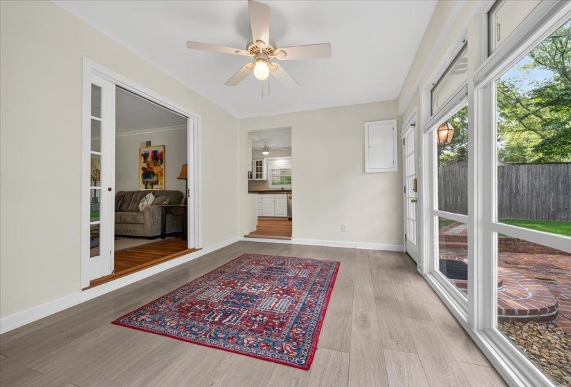 Sunroom featuring light wood-finish flooring, a ceiling fan with integrated lighting, and multiple large windows with white frames