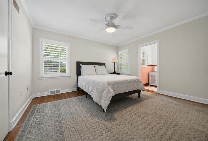 Bedroom featuring hardwood flooring, white baseboards, crown molding, and a ceiling fan with integrated lighting