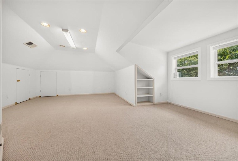 Carpeted room featuring dual windows, recessed lighting, and a built-in shelving unit