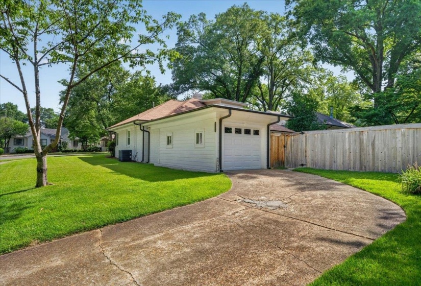White siding exterior with a single-car garage, concrete driveway, and a wooden privacy fence