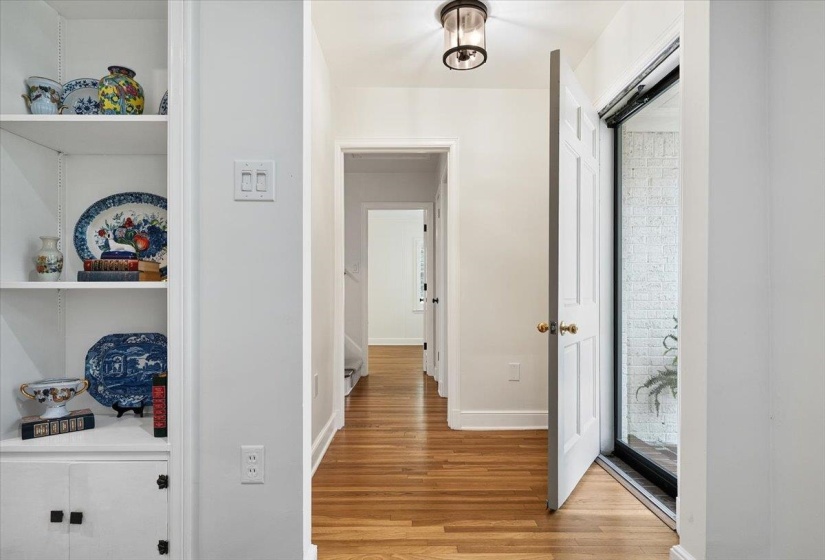 Hardwood flooring extends throughout this interior hallway, featuring a built-in shelving unit with lower cabinetry
