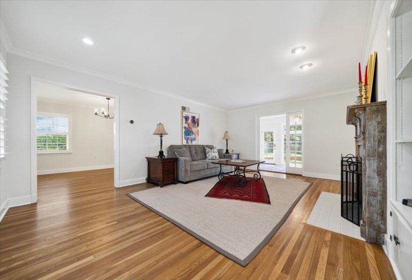 Spacious living area featuring wood-finish flooring, a decorative fireplace, recessed lighting, and white built-in shelving