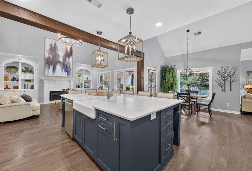 Spacious kitchen island featuring a farmhouse sink, stainless steel dishwasher, and quartz countertop