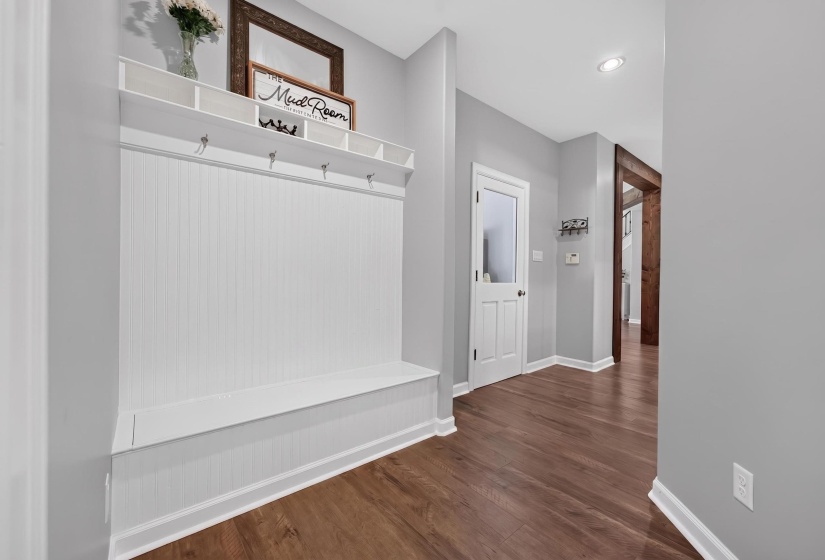 Entryway featuring a built-in bench with beadboard backing, overhead shelving, and coat hooks