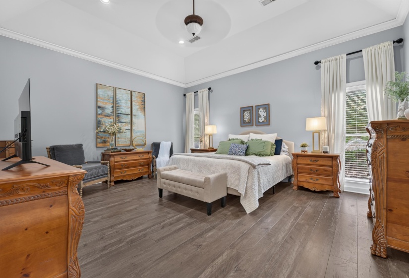 Spacious bedroom featuring wood-finish flooring, a vaulted ceiling with a ceiling fan, and crown molding