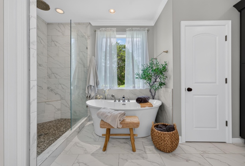 Freestanding soaking tub and glass-enclosed shower with pebble flooring