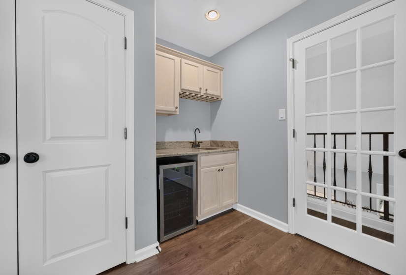 Wet bar area featuring light wood-finish cabinetry, a stone-finish countertop, and an under-counter beverage refrigerator