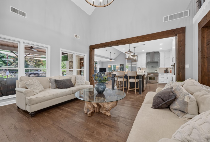 Spacious living area featuring wood-finish flooring, high vaulted ceilings, and large windows