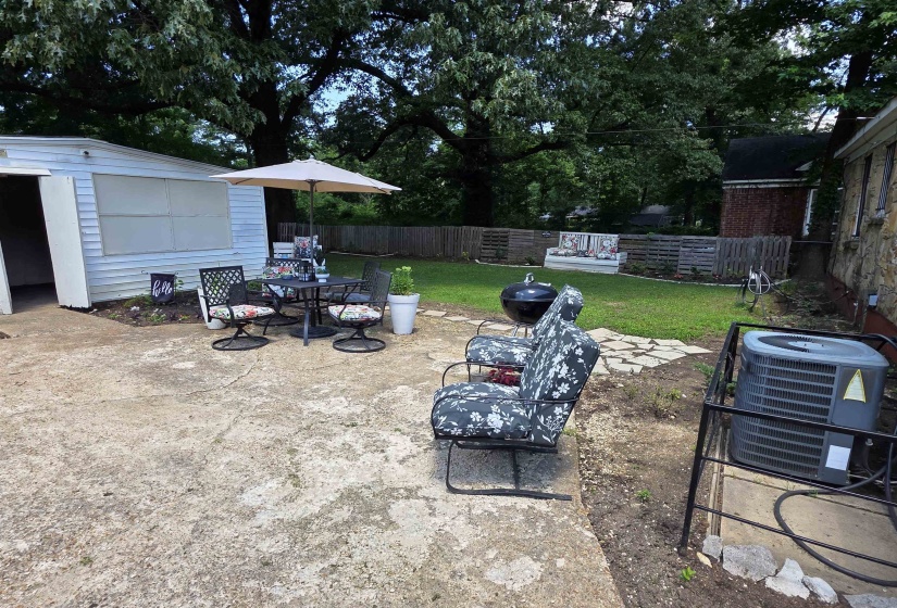 Expansive concrete patio area with a detached storage building