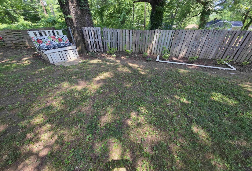 Expansive backyard featuring a wood fence, established trees, and a garden bed