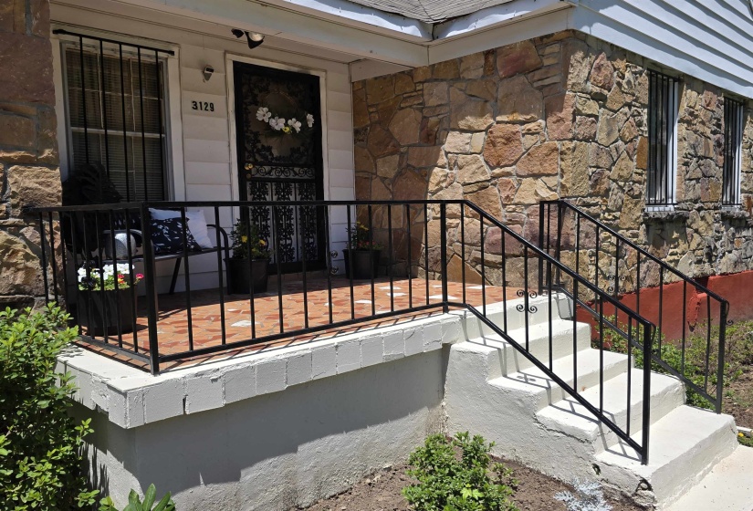 Stone veneer exterior with white siding accents and security bars on windows