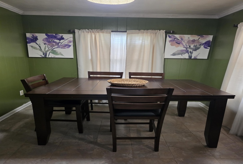 Dining area featuring wainscoting with a textured finish, crown molding, and neutral-toned flooring