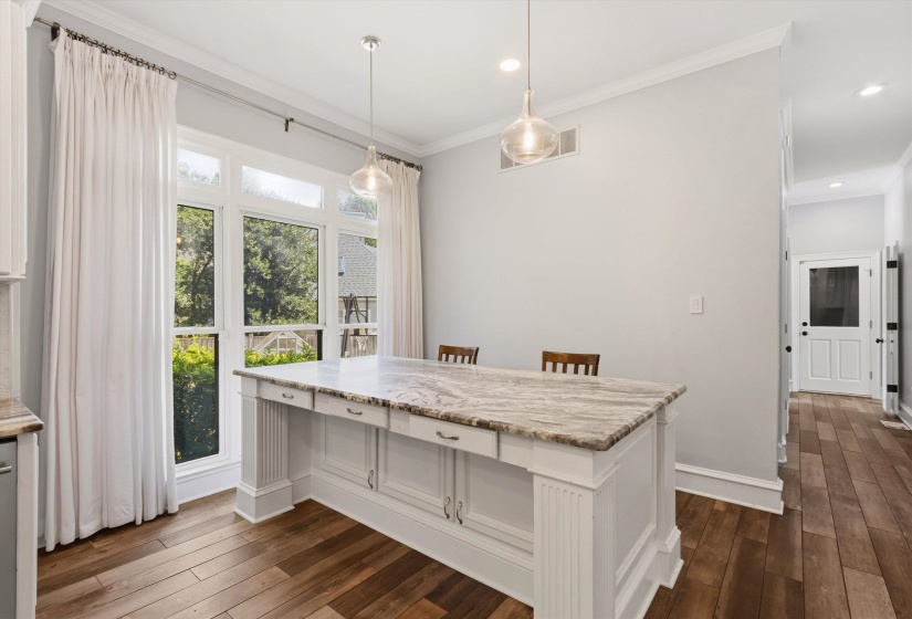 Kitchen island featuring a patterned stone countertop, white paneled base, and integrated storage drawers