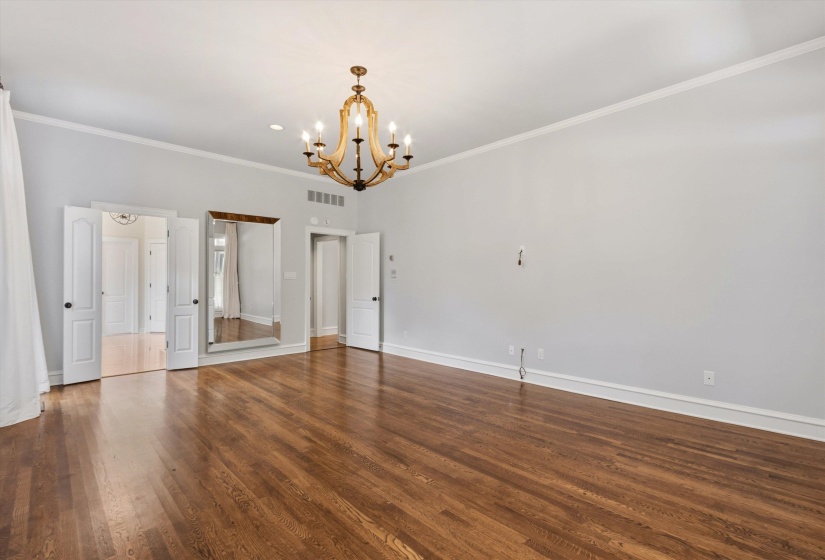 Spacious room featuring wood-finish flooring, a multi-arm chandelier, and crown molding