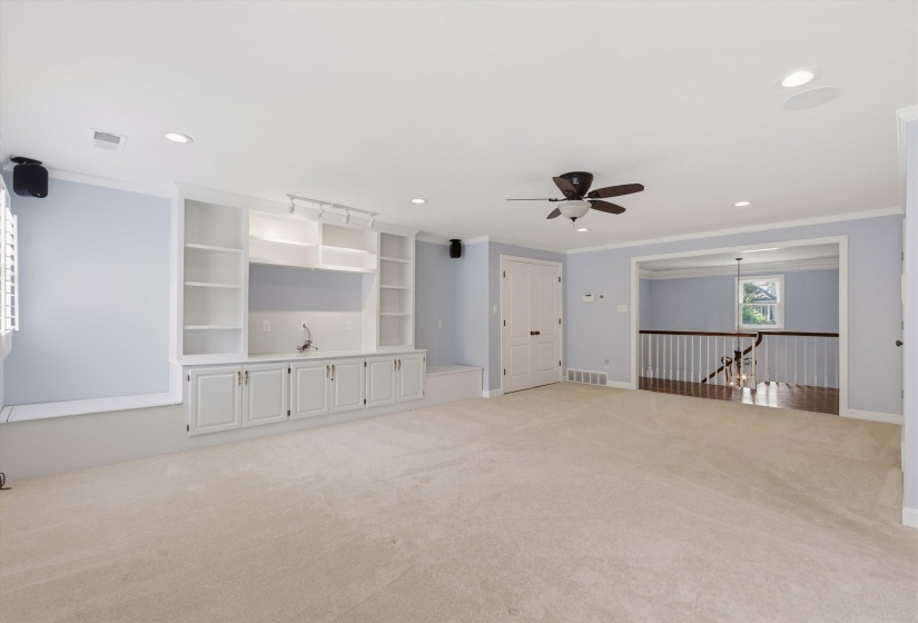 Spacious room featuring a built-in entertainment center with open shelving and lower cabinetry, a built-in wet bar with a sink, recessed lighting, and a ceiling fan