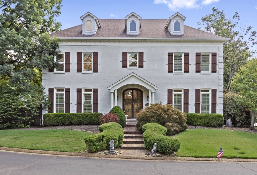 Traditional-style residence featuring a light-colored brick exterior with dark shutters