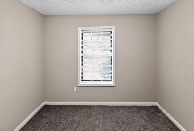 Spare room featuring dark carpet and a textured ceiling