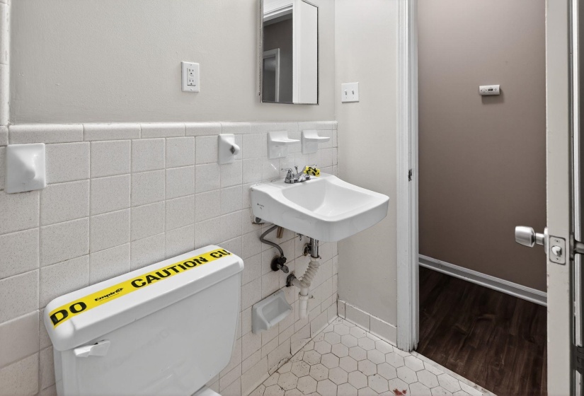 Half bath with tile walls and wood finished floors
