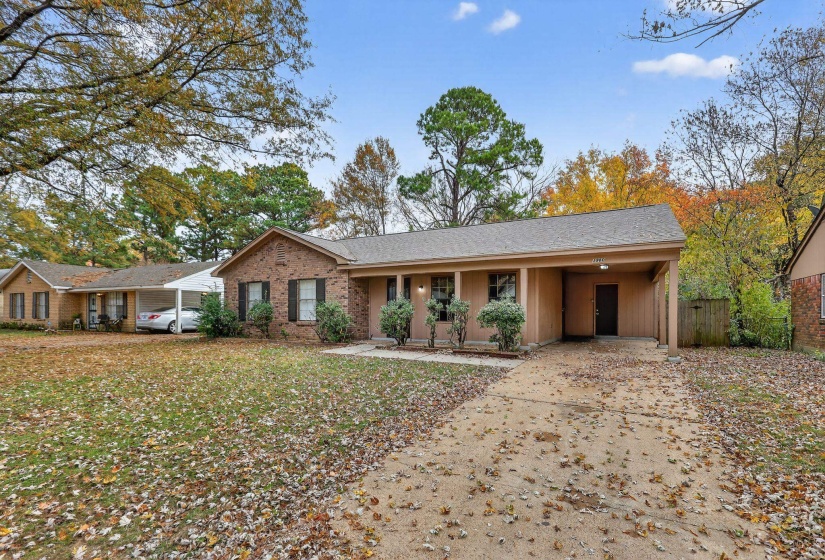 Ranch-style home featuring a carport, driveway, brick siding, and covered porch