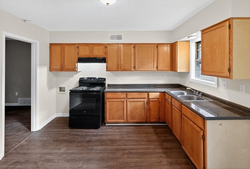 Kitchen with dark countertops, black / electric stove, dark wood finished floors, and brown cabinets