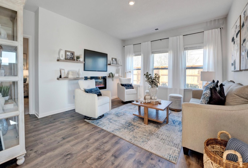 Living room featuring wood finished floors, a glass covered fireplace, and recessed lighting