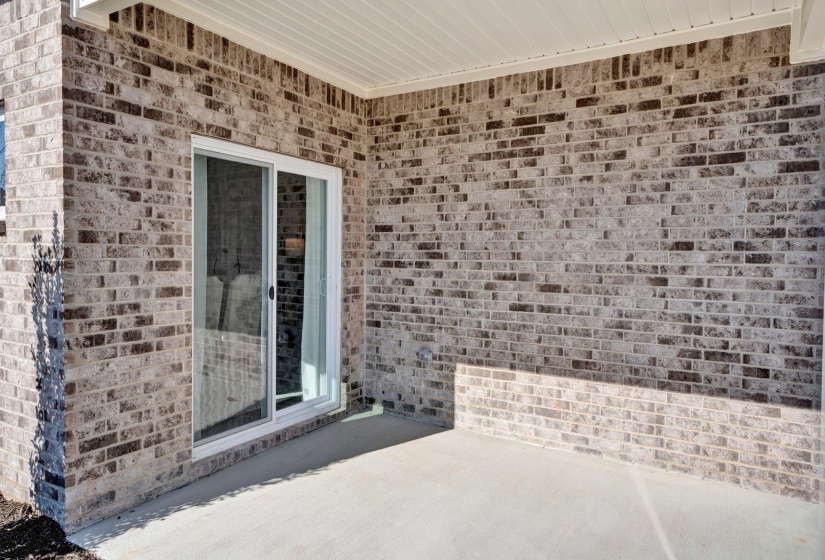 Property entrance featuring brick siding and a patio area