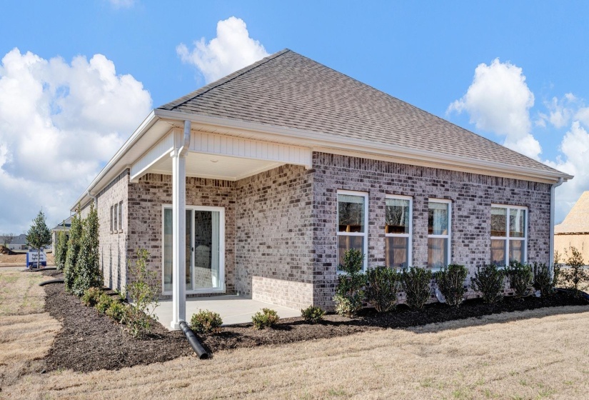 View of property exterior with brick siding, a patio, and roof with shingles