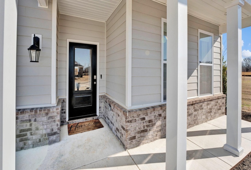 Entrance to property featuring covered porch and brick siding