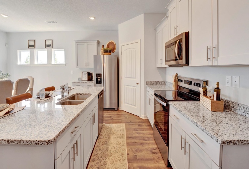 Kitchen with appliances with stainless steel finishes, a kitchen island with sink, light stone counters, light wood-style flooring, and recessed lighting