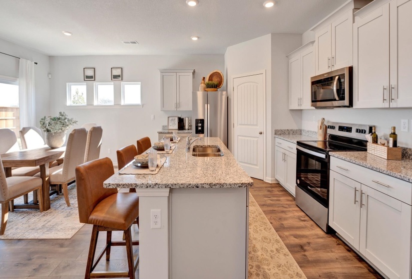 Kitchen featuring a kitchen breakfast bar, appliances with stainless steel finishes, light wood finished floors, recessed lighting, and light stone countertops
