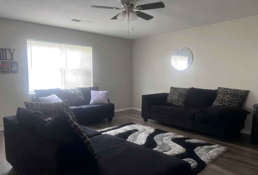 Spacious living area featuring neutral wall tones and wood-finish flooring