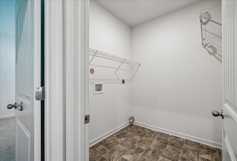 Dedicated utility space featuring durable tile flooring, white walls, and two wire shelving units for storage
