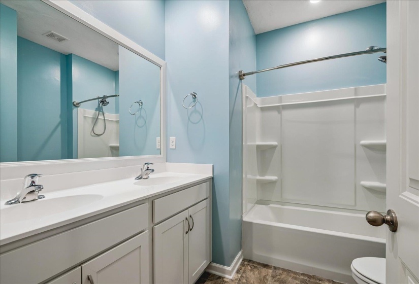 Double vanity with white countertop and integrated sinks, chrome faucets, and white cabinetry